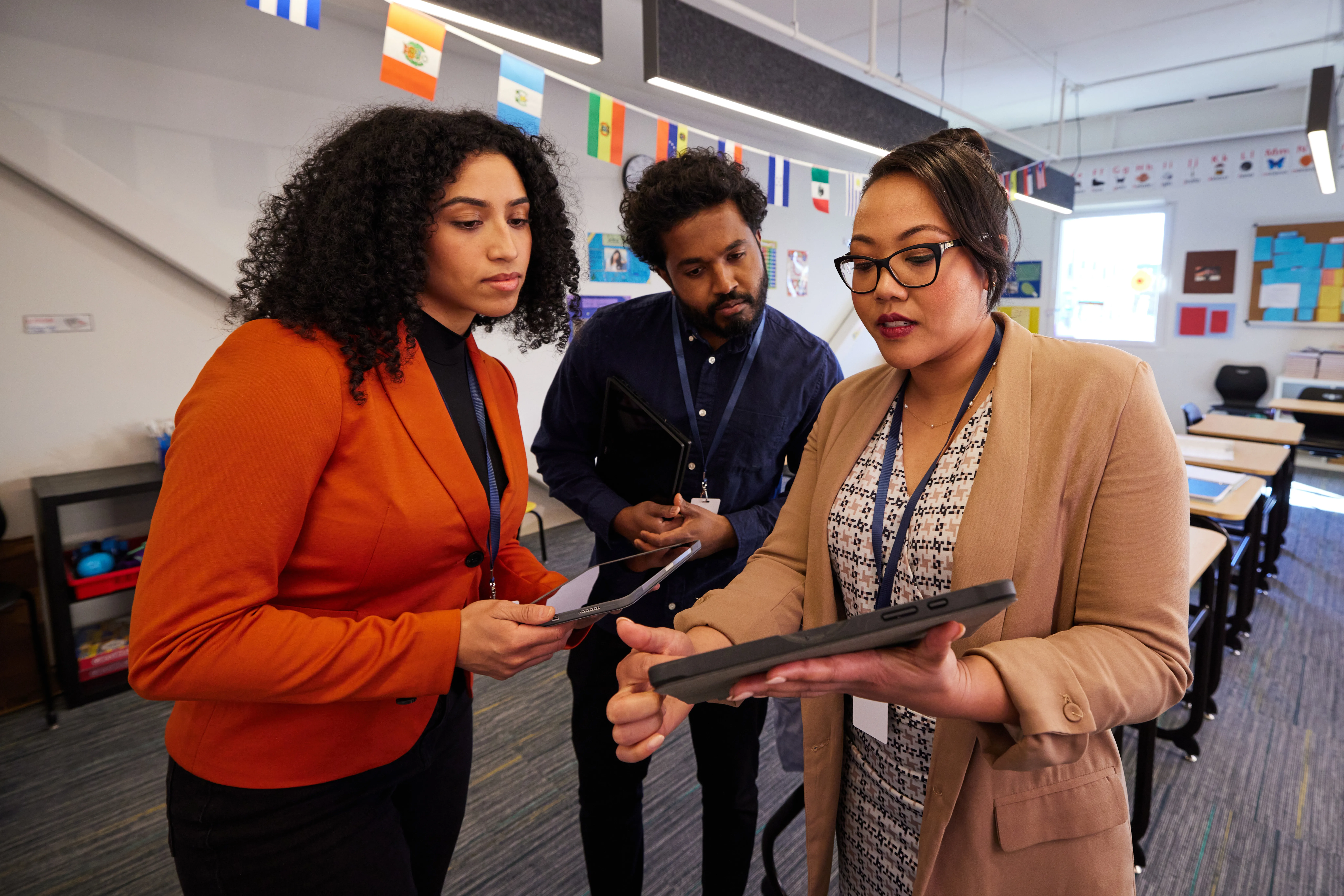 Group of teachers smiling and looking at an ipad